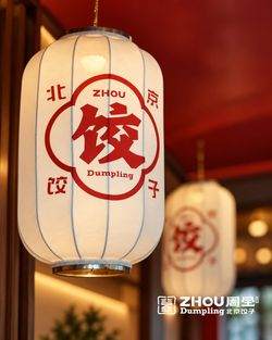 Lanterne chinoise décorative portant le logo de Zhou Dumpling dans un intérieur de restaurant asiatique.