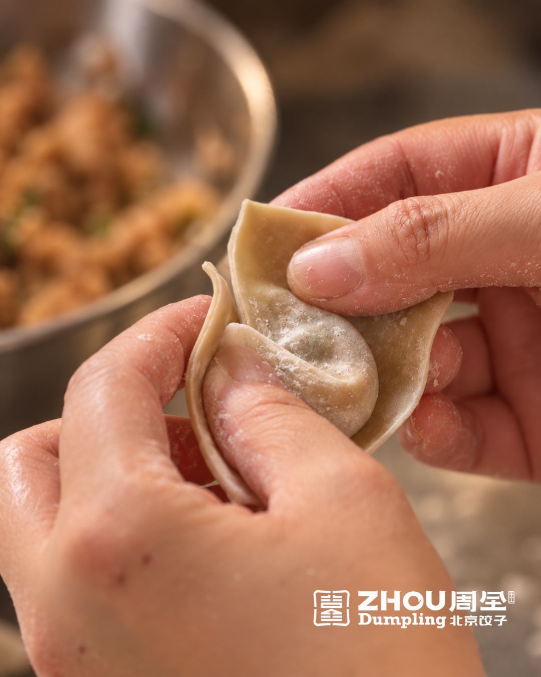 Mains façonnant à la main un ravioli chinois avec garniture en arrière-plan, spécialité du restaurant ZHOU DUMPLING.
